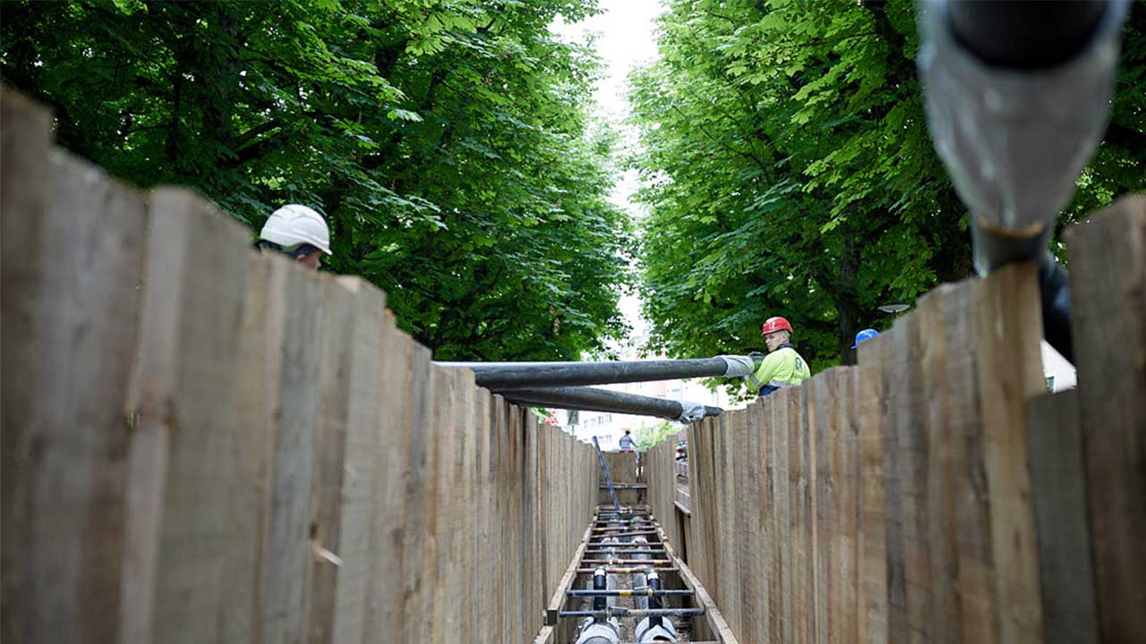 Offener Graben mit Fernwärmeleitungen und Holzspriessungen auf der Seite