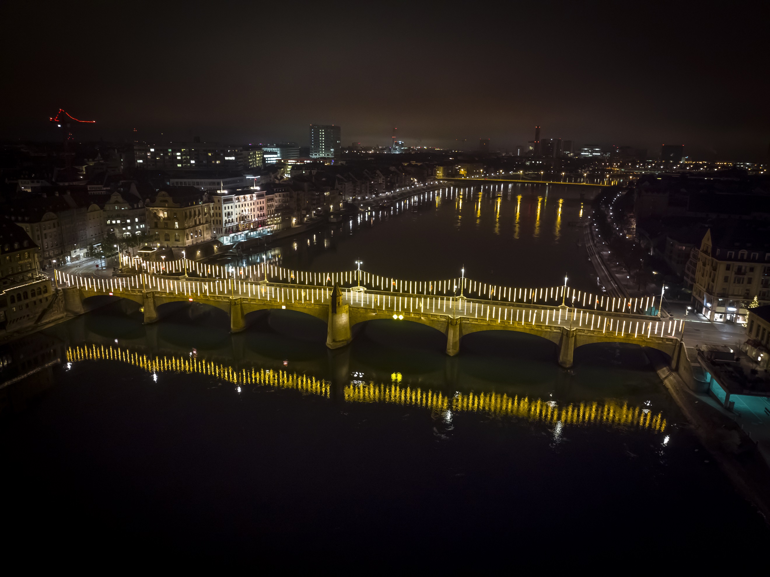 IWB Mitarbeitender installiert die Weihnachtsbeleuchtung auf der Mittleren Brücke in Basel