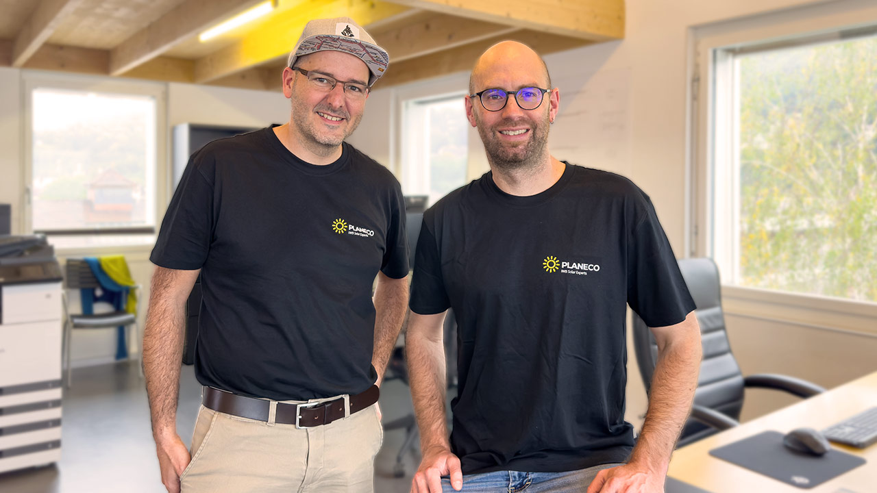 Zwei Männer in PLANECO-T-Shirts stehen in einem Büro und lächeln in die Kamera.